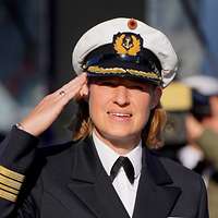 Eine Soldatin grüßt mit flacher Hand an der Kopfbedeckung