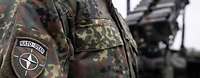 Ein Soldat mit einem NATO-Ärmelabzeichen steht vor dem Waffensystem Patriot 