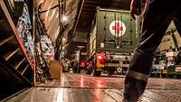 Ein Lkw mit rotem Kreuz steht in einem Laderaum eines Flugzeugs.
