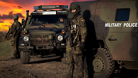 Soldaten stehen an einem Feldjägerfahrzeug und beobachten die Umgebung