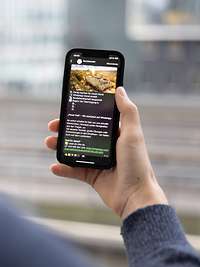 Eine Person hält ein Handy in der Hand auf dem ein Kanal von der Bundeswehr zu sehen ist.