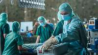Meherer Personen in OP-Kleidung stehen um ein OP-Tisch