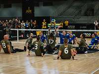 Deutsche und ukrainische Sportler spielen Sitzvolleyball in einer Halle