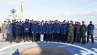 Gruppenfoto mit mehreren Personen auf dem Flugdeck eines Kriegsschiffes.