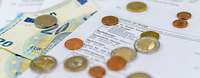 Eurobanknoten und Euromünzen liegen auf einer Lohnbescheinigung