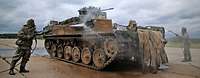 Soldaten in Schutzanzügen säubern einen Schützenpanzer