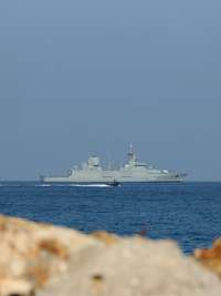 Ein graues Marineschiff von Land aus gesehen.