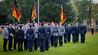 Soldatinnen und Soldaten stehen angetreten in Formation zum Gelöbnis auf einer Wiese.