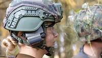 Eine Soldatin mit Helm und Gehörschutz im Profil.