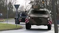 Two wheeled armoured fighting vehicles are driving on a road one behind the other.