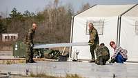 Several Bundeswehr soldiers setting up a tent