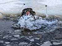 Ein Soldat ist in einen zugefrorenen See eingebrochen, bis zur Brust ist er schon im dunklen Wasser.