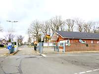 Eine Einfahrt mit einer Schranke, daneben ein Gebäude in der Größe eines Einfamilienhauses