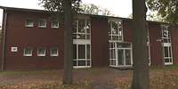 Ein rotes Backsteingebäude mit zwei Bäumen davor