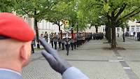 Militärmusiker marschieren auf einen grüßenden Soldaten zu