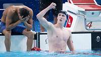 Ein Schwimmer im Schwimmbecken in Jubelpose und gestreckter Faust nach oben