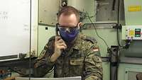 Oberstleutnant Markus König sitzt in einer Kabine und telefoniert.