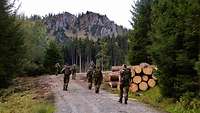 Soldaten marschieren mit Rucksack auf einem Waldweg.