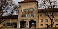Gebäudefront mit 2 Durchfahrtstoren in einem Turm.