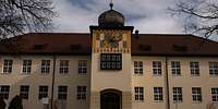 Hausfassade mit einem Turm im mittleren Gebäudeteil.