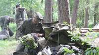 Ein Soldat kniet vor seinem Zelt und packt seinen Rucksack.
