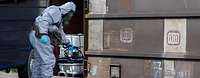 Ein Mensch in Schutzanzug hält ein Gerät an einen Eisenbahnwaggon