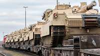 Mehrere beige Panzer hintereinander auf einem Zug
