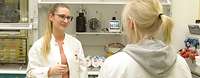 Zwei Frauen stehen in einem Labor gegenüber.