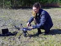 Eine Zivilisten hockt am Boden und arbeitet dabei an einer Flugdrohne