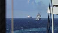 Bild von zwei Schiffen, vorderes Schiff ein graues Kriegsschiff, dahinter ein Containerschiff