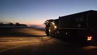 Ein Tankfahrzeug steht bei Nacht auf dem Flugfeld.