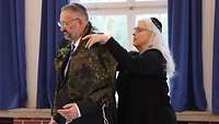 Eine Rabbinerin legt einem Militärrabbiner einen Gebetsmantel mit Flecktarnmuster über die Schulter.