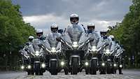 Sieben Motorräder der Feldjäger stehen in Formation auf einer Straße