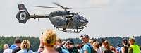 Zuschauer beobachten einen Hubschrauber vom Typ H145M LUH SOF im Tiefflug während einer Flugshow