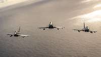 Aus der Vogelperspektive sieht man über offenem Gewässer drei Eurofighter im Flug.