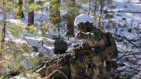 Zwei bewaffnete Soldaten knien und stehen im verschneiten Gelände