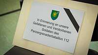 Ein Schild erinnert an Gefallene und Verstorbene