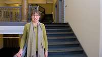 Eine Frau steht auf einer Treppe und lehnt sich an ein Treppengeländer.