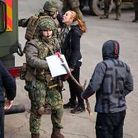 Menschengruppe aus Zivilisten (Schauspieler) mit Schildern und Soldaten