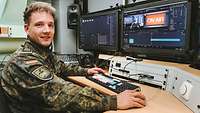Ein Soldat sitzt am Schreibtisch vor einer Computeranlage.