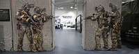Vier Soldaten in Kampfanzügen mit Maschinenpistolen in einer Ausstellungshalle