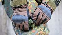 Ein Soldat zieht am Abzugsring einer Handgranate DM51
