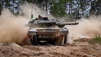 Ein Kampfpanzer Leopard 2A7V fährt im Gelände und wirbelt Staub auf