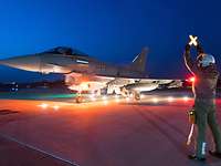 Ein Eurofighter steht beleuchtet auf der „Platte“. Ein Soldat gibt Lichtzeichen.