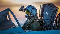 Ein Pilot mit Nachtsichtbrille sitzt in einem Kampfjet.