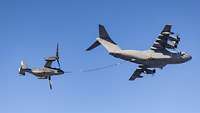 Ein Kipprotor-Flugzeug hängt am Betankungsschlauch eines Airbus A400M während des Fluges