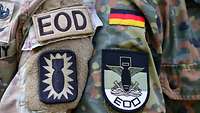 Die Arme von zwei Soldaten mit je einem Patch mit Bombe von der US-Armee und der Bundeswehr.