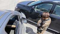 Eine Soldatin steht zwischen zwei Fahrzeugen, die scheinbar einen Unfall gebaut haben. Sie fotografiert die Fahrzeuge