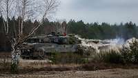 Ein Kampfpanzer kurz nach der Schussabgabe noch im Staub gehüllt.
