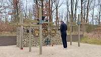 Ein Mensch steht zwischen Kreuzen an einer Gedenkmauer